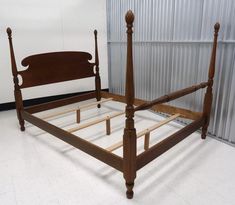 a bed with wooden posts and headboard in a room