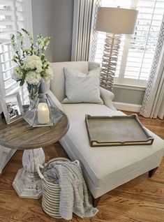 a living room filled with furniture and flowers on top of a coffee table in front of a window