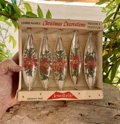 four wine glasses in a box with christmas decorations on the bottom and red poinsettis