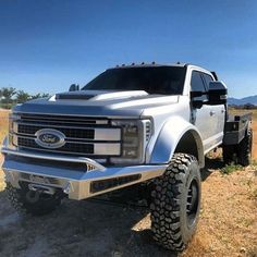 a large white truck parked on top of a dry grass field