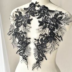 the back of a mannequin with black lace and flowers on it's neck