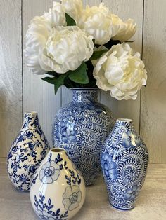 three blue and white vases with flowers in them