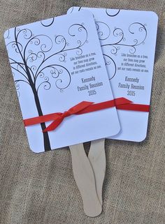 two wedding cards with red ribbon tied around them on top of a wooden spatula