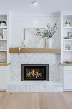 a fireplace in a living room with white walls and wood flooring on the side