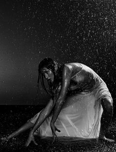 a black and white photo of a woman in the rain with her legs spread out