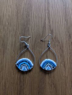 two pairs of blue and white beaded earrings on a wooden surface with silver hooks