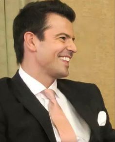 a man wearing a suit and tie smiling