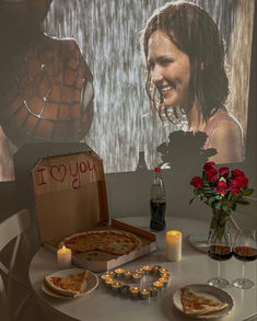 a table topped with pizza and candles next to a vase filled with flowers on top of it