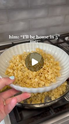 a person is holding a bowl with macaroni and cheese in it on the stove