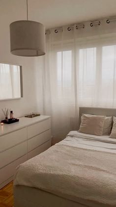 a bedroom with white furniture and large windows