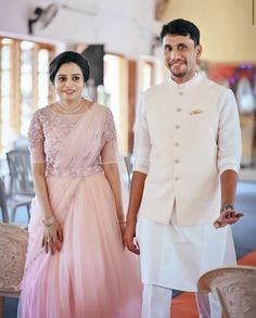 a man and woman standing next to each other in front of a table with chairs