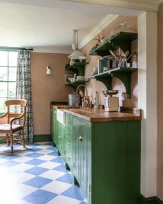 a kitchen with green cabinets and checkered flooring on the walls, along with a dining room table