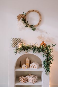 a white shelf with christmas decorations on it and a wreath hanging above the shelves next to it