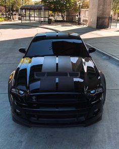 a black mustang with white stripes parked on the street