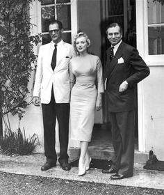 two men and a woman standing in front of a house