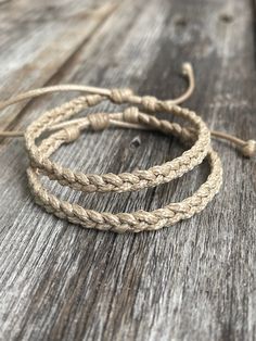 three braided bracelets sitting on top of a wooden table