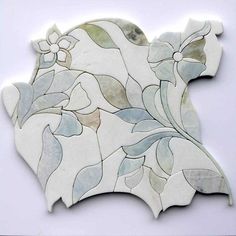 a white and blue tile with flowers on it's side, in the shape of a flower