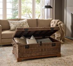 an open trunk sitting on top of a rug in a living room next to a couch