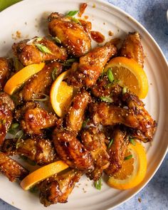 a white plate topped with chicken wings covered in orange slices