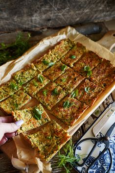 a person is cutting into a pizza on top of a wooden table next to utensils