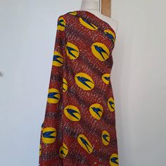 a red and yellow dress on a mannequin's head stand in front of a white wall