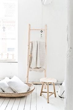 a room with white walls and wooden flooring has a ladder leaning up against the wall