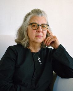 an older woman wearing glasses sitting on a chair