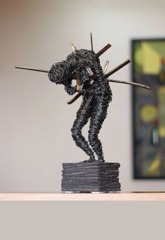 a statue of a man holding two swords on top of a stack of stacks of books