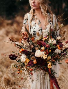 a woman holding a large bouquet of flowers in her hands and wearing a white dress