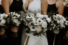 a group of bridesmaids holding bouquets of white and black flowers in their hands