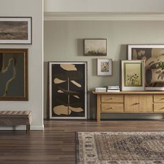 a living room filled with furniture and framed pictures on the wall above a wooden table