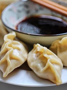 dumplings on a plate with chopsticks and sauce in a bowl next to them