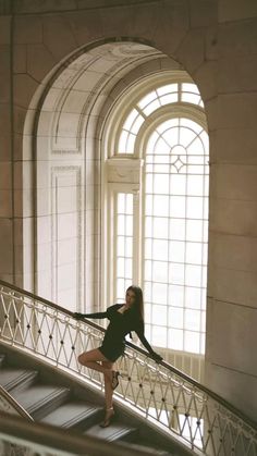 a woman standing on top of a metal handrail in front of a large window