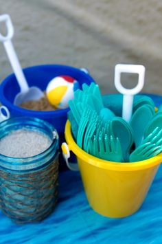 a yellow bucket filled with plastic utensils on top of a blue table