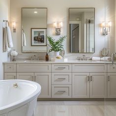 a large white bath tub sitting next to two sinks in a bathroom with mirrors on the wall