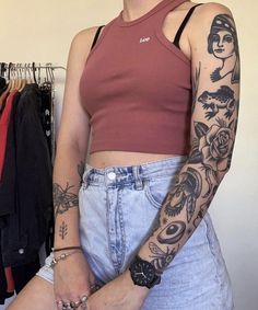 a woman with tattoos on her arm standing in front of clothes