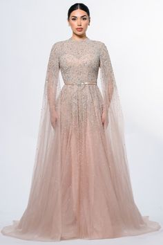 Experience understated elegance with the Noor Modest Long Drape Sleeves Beaded A-line Gown by Iyza Belaar. This evening gown features a unique blend of modesty and glamour, with long cape sleeves gracefully touching the floor and a delicate beaded bodice that seamlessly transitions into a tulle beaded skirt. Hand-embellished with meticulous attention to detail, this gown is a captivating choice for those seeking timeless sophistication at formal events. Tulle A-line Gown: The Noor Gown is crafted from a hand-embellished Tulle Overlay Fabric, offering a luxurious and ethereal quality to the dress. The partially lined bodice provides a hint of allure, while the fully lined skirt guarantees coverage. The semi-sheer unlined sleeves add a touch of delicacy, allowing you to showcase a modest yet Gowns Aesthetic, Long Drapes, Long Cape, Evening Gowns With Sleeves, Beaded Skirt, Drape Sleeves, Cape Sleeves, Beaded Bodice, Glamorous Style