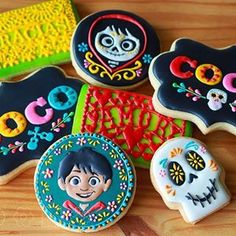 decorated sugar cookies on a wooden table with colorful decorations and skulls in the shape of people's faces