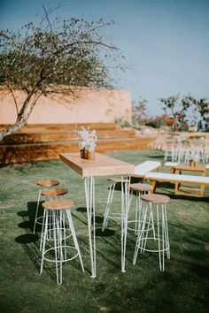 an outdoor table and stools set up in the grass with flowers on each side