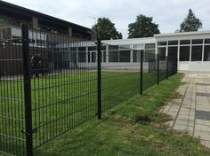 a black fence is in front of a building and some green grass on the ground