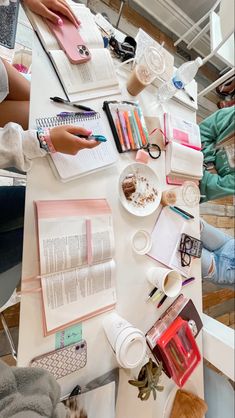 people sitting at a table with notebooks, pens and papers on top of it