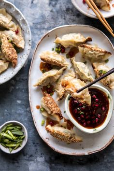 two plates with dumplings and dipping sauce on them