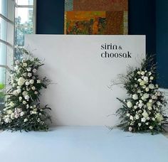 two white flowers sitting on top of a table next to a sign that says siro & chooshk