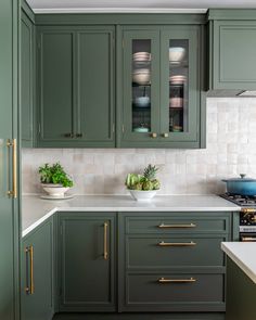 a kitchen with green cabinets and white counter tops