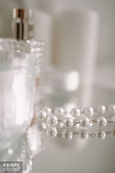 pearls and perfume bottles sitting on a table with soap dispenser in the background