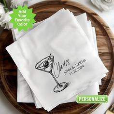 personalized cocktail napkins on a wooden plate with white flowers and greenery in the background