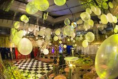 a room filled with lots of balloons floating in the air and lights hanging from the ceiling