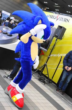 a blue sonic mascot standing on top of a red shoe