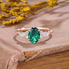 a green ring with white stones on top of a wooden table next to yellow flowers