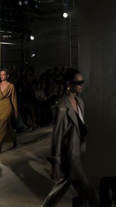 two models walking down the runway in front of a large group of people wearing sunglasses